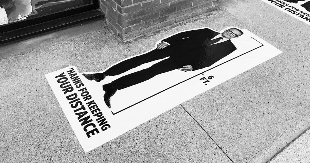 6-feet long decal sticker stuck flat on the ground with image of Tom Hanks standing and text 'Hanks for keeping your distance'