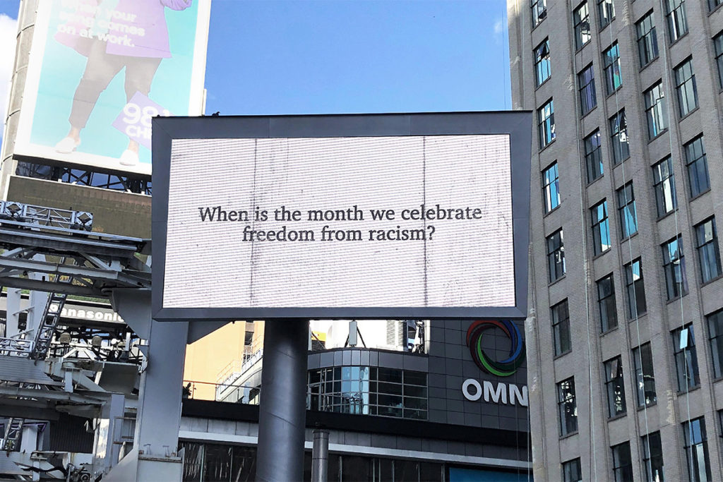 Billboard on Yonge-Dundas square with text "When is the month we celebrate freedom from racism?"