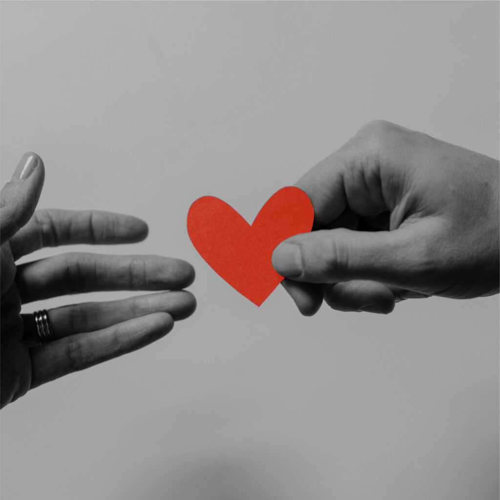 Two hands passing a paper heart between them