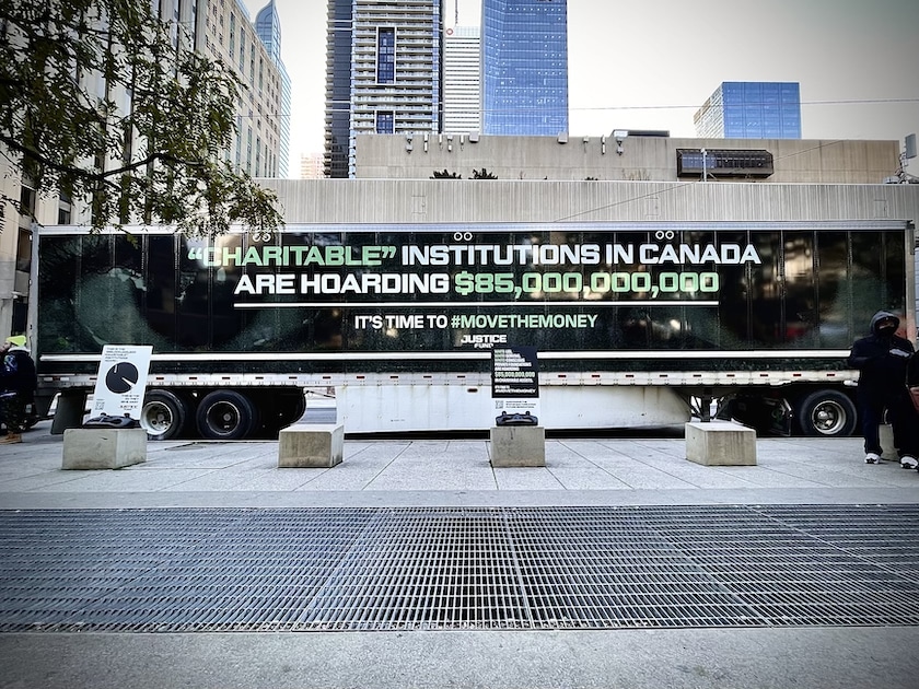 A truck outside City Hall which reads: "Charitable" foundations in Canada are hoarding $85 Billion dollars. It's time to #MoveTheMoney